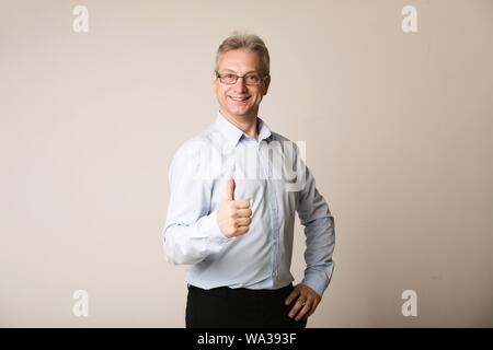 Mature businessman showing thumb up, smiling to camera Stock Photo