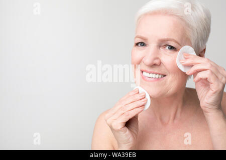 Mature woman using cotton pad for removing make up Stock Photo