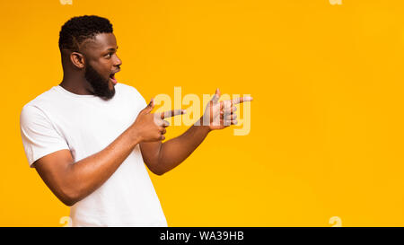 Excited black man pointing two fingers aside at copy space Stock Photo