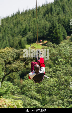 A young Kenyan man travelling on a zip line at The Forest recreation centre, Kenya Stock Photo