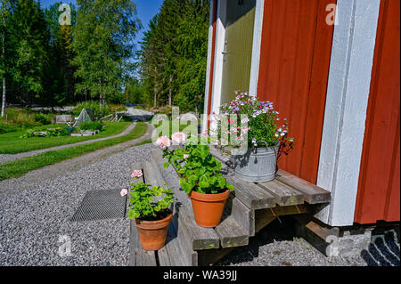 flowers on stairs infront of a red wooden cabin Stock Photo