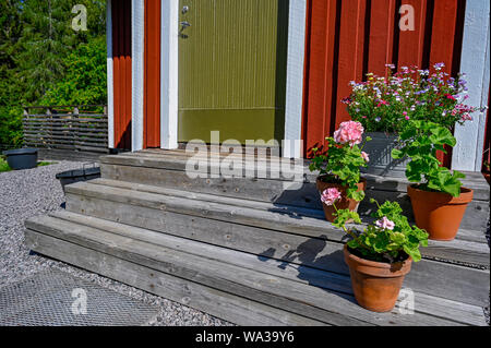 flowers on stairs infront of a red wooden cabin Stock Photo