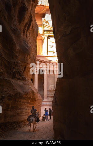 Petra, Jordan - April 06, 2015: Bedouin riding a mule at the end of the Siq, coming out in front of the Treasury, one of the most elaborate temples Stock Photo