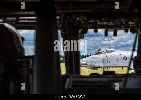 An A-10C Thunderbolt II passes in front of an HH-60G Pave Hawk before the Pave Hawk crew leaves for National Night Out, Aug. 6, 2019, at Moody Air Force Base, Ga. National Night Out is an annual event that promotes relationships between police and the community in an effort to prevent crime. Representatives from Team Moody participated to drive community interest in their mission. (U.S. Air Force photo by Airman 1st Class Hayden Legg) Stock Photo