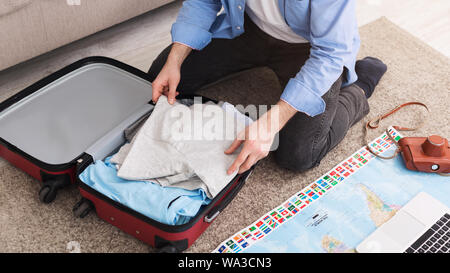 Man packing suitcase at home, sitting on floor Stock Photo