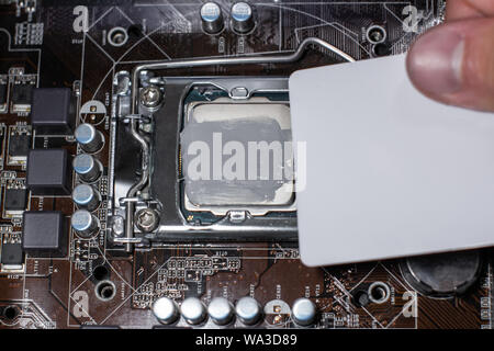 Close up to technician squeezing or application the thermal paste compound on the top of main cpu in the socket. Concept of repairing or upgrading com Stock Photo