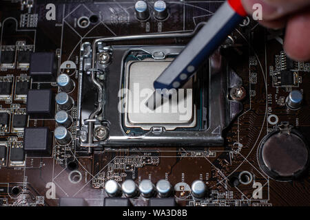 Close up to technician squeezing or application the thermal paste compound on the top of main cpu in the socket. Concept of repairing or upgrading com Stock Photo