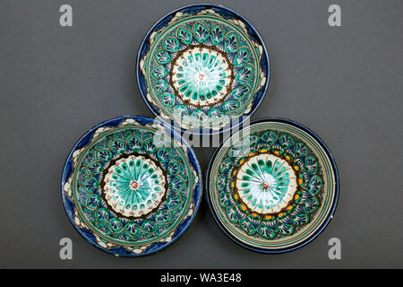 Ethnic Uzbek ceramic tableware on the gray background. Decorative ceramic cups with traditional uzbekistan ornament.