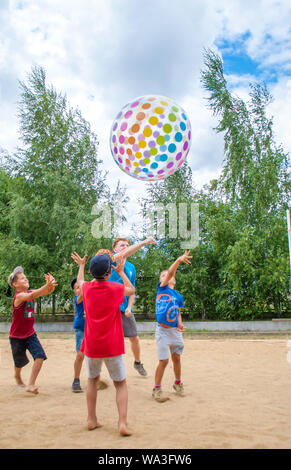 Odesa rgn. Ukraine, July 15, 2018: Boys playing with a big colored ball, throwing it through the net in the summer camp. Stock Photo