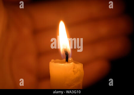 A burning candle protected by the hand of a man. Shallow depth of field. Stock Photo