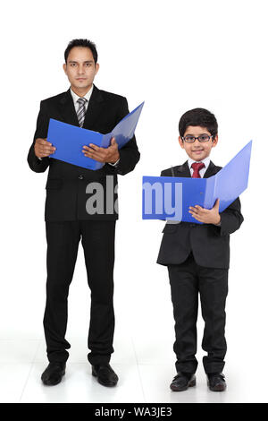 Boy imitating as a businessman and standing with his father Stock Photo