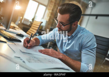 New project. Busy bearded engineer in eyeglasses and formal wear drawing something while working in the office. Engineer. Construction plan