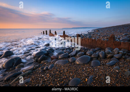 Waves crash over the rock and against an old groyne at westward Ho! beach in North Devon Stock Photo