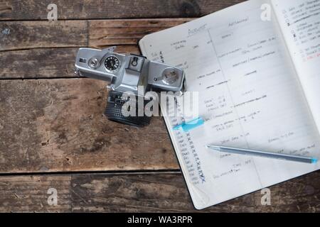 Overhead shot of a professional photo camera next to an organizer textbook of a photographer Stock Photo