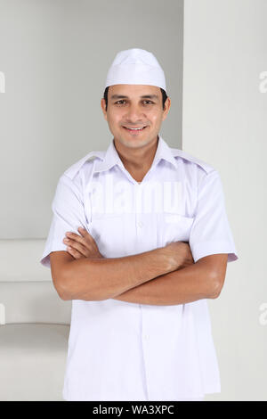 Peon standing with his arms crossed in office Stock Photo