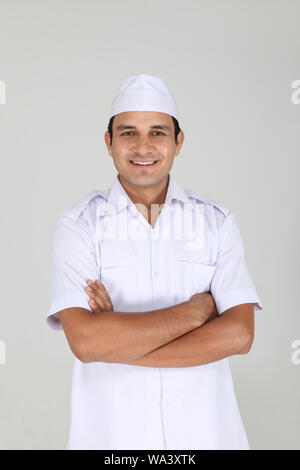 Peon standing with his arms crossed in office Stock Photo