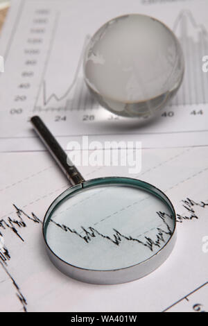 Close up of a globe with magnifying glass on graphs Stock Photo