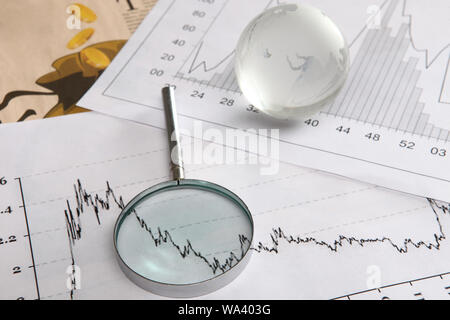 Close up of a globe with magnifying glass on graphs Stock Photo