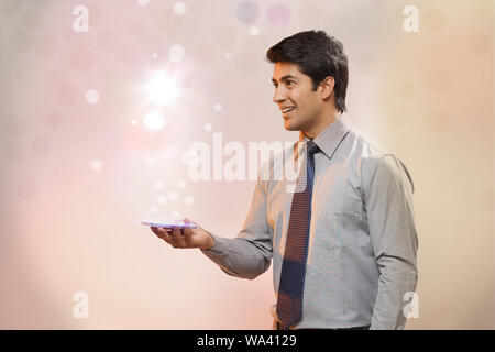 Businessman looking at lights coming from a smart phone Stock Photo