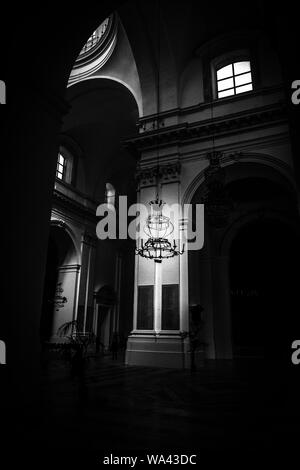 Vertical shot of a candle holder chandelier hanging from the ceiling in black and white Stock Photo