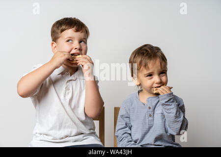 Group of classmates having lunch during break with focus on smiling kids with sandwiches. Pizza at school. Eating together. Stock Photo