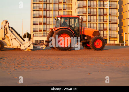 MORNING SWEEP: A tractor with an attached sifting device cleans and removes garbage from Virginia beach in the early dawn hours. Stock Photo