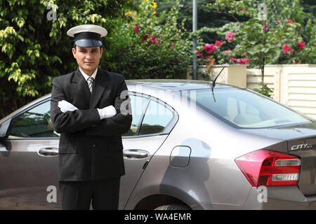Chauffeur standing with his arms crossed at a car Stock Photo