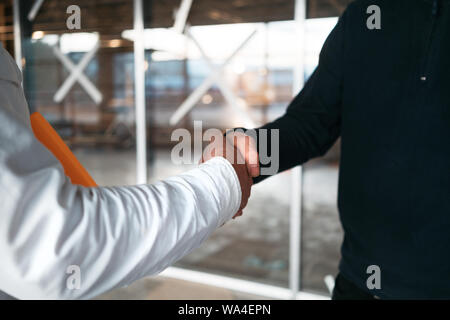Architect and building engineer have handshake on construction site. Building workers shaking hand inside industrial object Stock Photo
