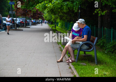 Polish Tatras, Poland June 12, 2019: Portrait of two active stylish traveler holding map in hands, choose the right route to the mountains, sitting on Stock Photo