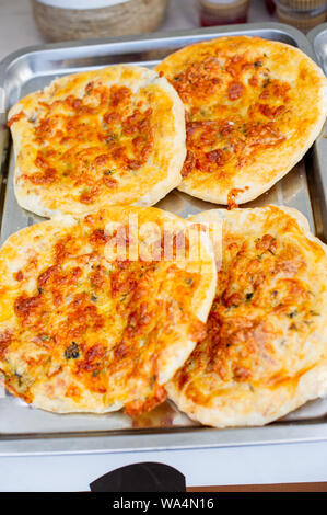 Tasty food. Four small pizzas lie on a metal tray and parchment. Street food. Italian food. Tomatoes and Dough. Small pizzas Stock Photo