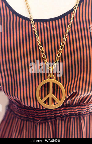 A giant peace sign necklace with a striped dress is a fun find at Zen and Now Pre-Loved Clothing in Asheville, NC, USA Stock Photo