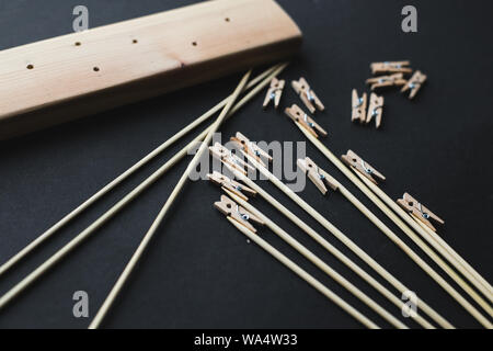 glue together wooden clothespins and sticks, make a holder for photos on a black background Stock Photo