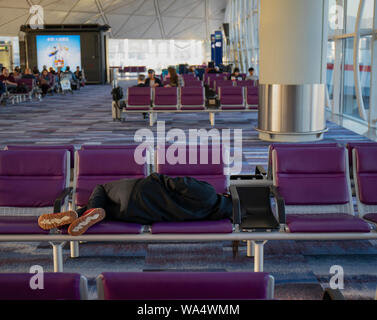 Hong Kong Airport, Hong Kong - October 29th, 2018: A young woman sleeping on seats at the Hong Kong airport