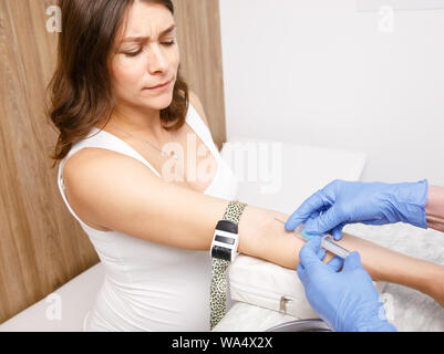 Medical assistant or nurse taking a blood sample from arm vein of pregnant woman with a vacutainer. Venipuncture or venepuncture procedure concept Stock Photo
