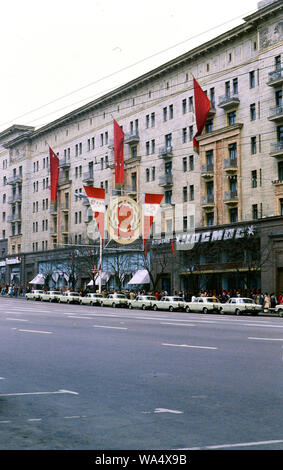 Large hammer and sickle banner outside a building in the Soviet Union in the late 1970s (1978), rows of similar white Russian cars parked in front Stock Photo