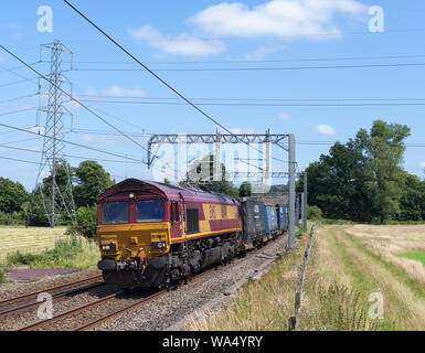 DB cargo class 66 locomotive passing Nether Alderley (south of Alderley Edge) with a intermodal container freight train for the haulier WH Malcolm LTD Stock Photo
