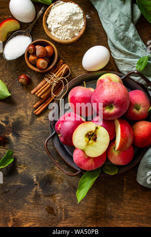 Apple baking seasonal concept. Ingredients for apple pie (red apple, flour, eggs, anise, sugar, hazelnut and cinnamon) on a rustic wooden table. Top v Stock Photo