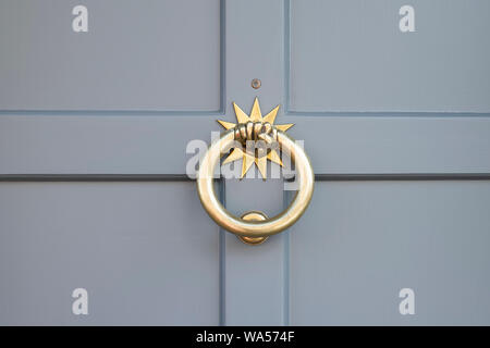 Brass hand star fist door knocker on a grey wooden house door. Stow on the wold, Gloucestershire, England Stock Photo