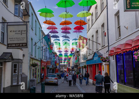 Multi-coloured umbrellas over Palace Street, Caernarfon, North Wales Stock Photo