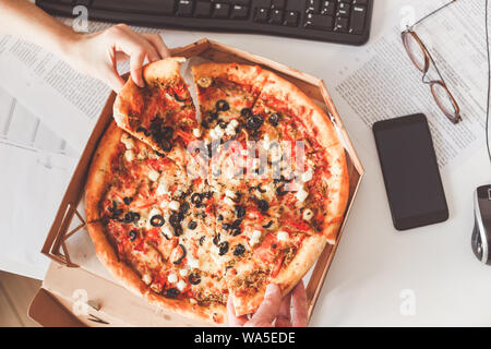 Business lunch at the workplace. Vegetarian pizza sharing. Stock Photo