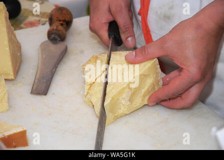 man cutting parmigiano on wooden board Stock Photo