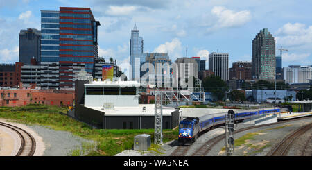 An Amtrak train leaves the Raleigh station with the skyline in the background. Viewed from the Boylan Heights neighborhood. Stock Photo