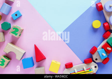 Kids toys: pyramid, wooden blocks, bear, train frame on colored background. Top view. Flat lay. Copy space for text Stock Photo