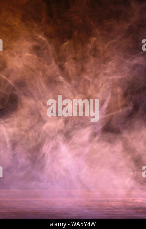 Conceptual image of multi-colored smoke isolated on dark black background and wooden table. Stock Photo