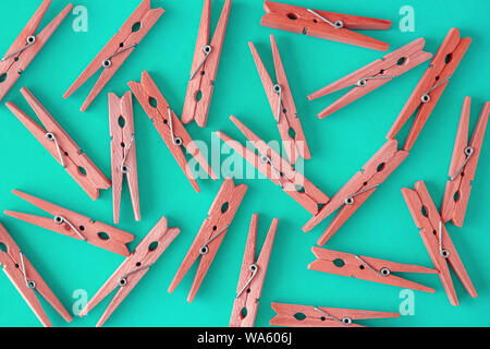 Wooden red clothespins are scattered on a blue-cyan-green background. Frame of clothespins. View from above. Copy space. Flat lay. The concept is natu Stock Photo
