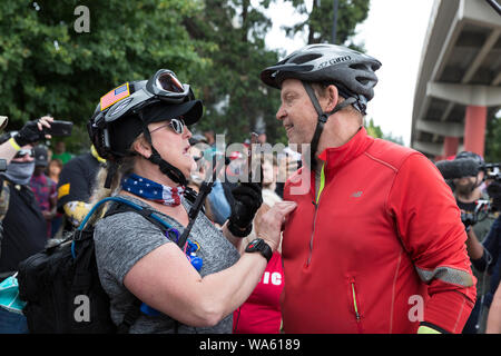 A alt-right protester has a heated discussion with a cyclist who stumbled upon the “End Domestic Terrorism” rally at Tom McCall Waterfront Park on August 17, 2019 in Portland, Oregon. Organized as a protest against anti-fascists by right-wing radio host Joe Biggs and members of the Proud Boys, the rally attracted a large contingent of counterprotesters including Rose City Antifa. Stock Photo