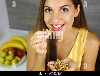 Smiling girl eating walnuts at home. Close up from above. Healthy concept. Stock Photo