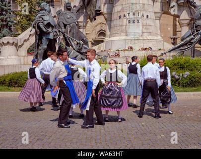 Hungarian Traditional dance in folkloric customs public performance in square. Males performing face slapping number under disapproving lady look Stock Photo
