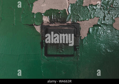 Concrete rural stove with closed metal doors and peeling green paints from the wall Stock Photo