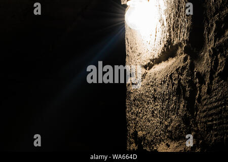 Lonely lamp illuminating brown concrete wall in absolute darkness with black area of copy space Stock Photo